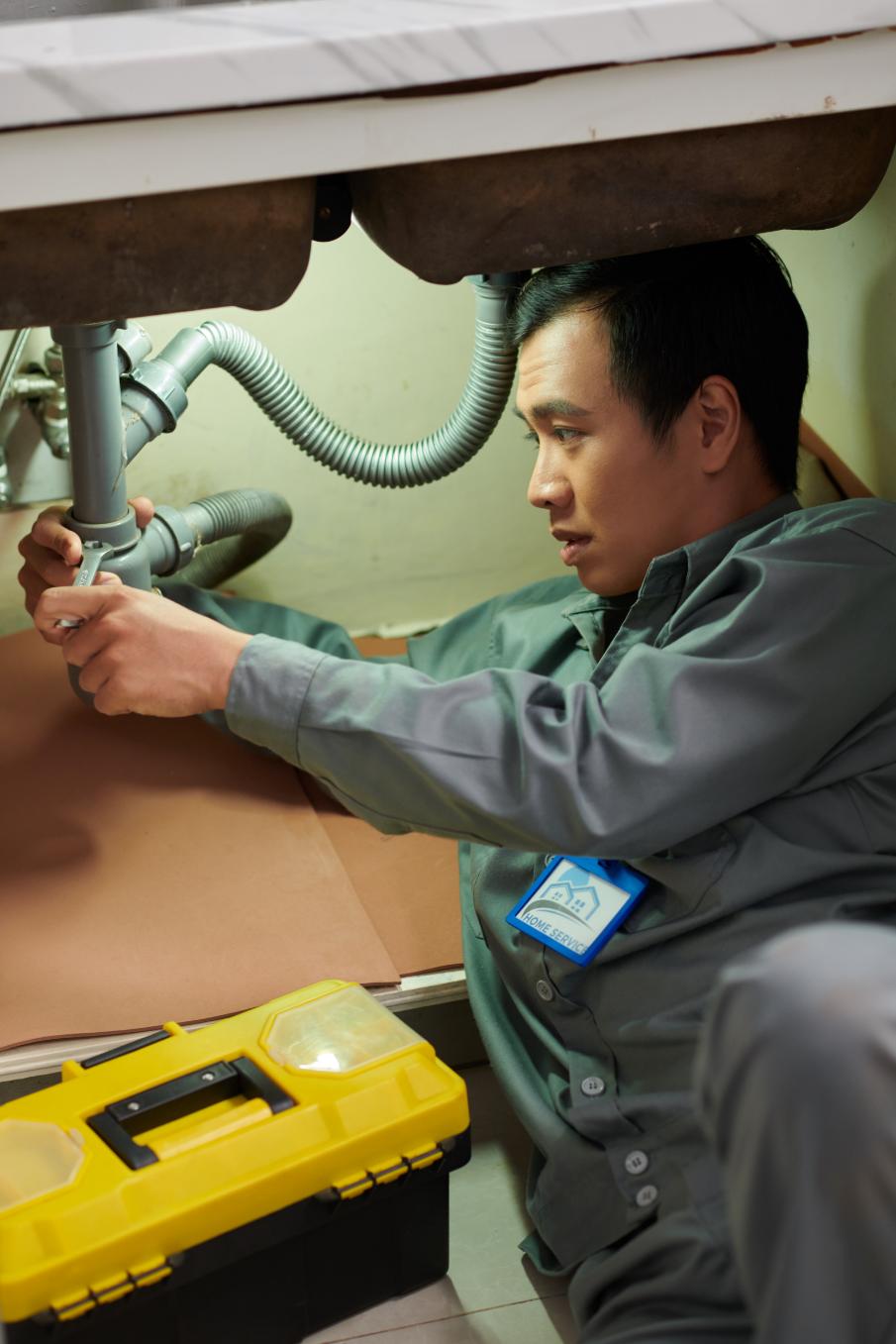 Professional plumber working on sink pipes with precision tools